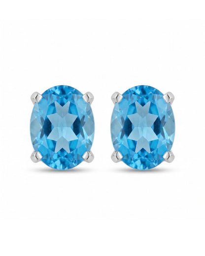 Aretes tipo topitos Riviera de Pedra con gema azul en corte ovalado y montura de cuatro garras sobre fondo blanco