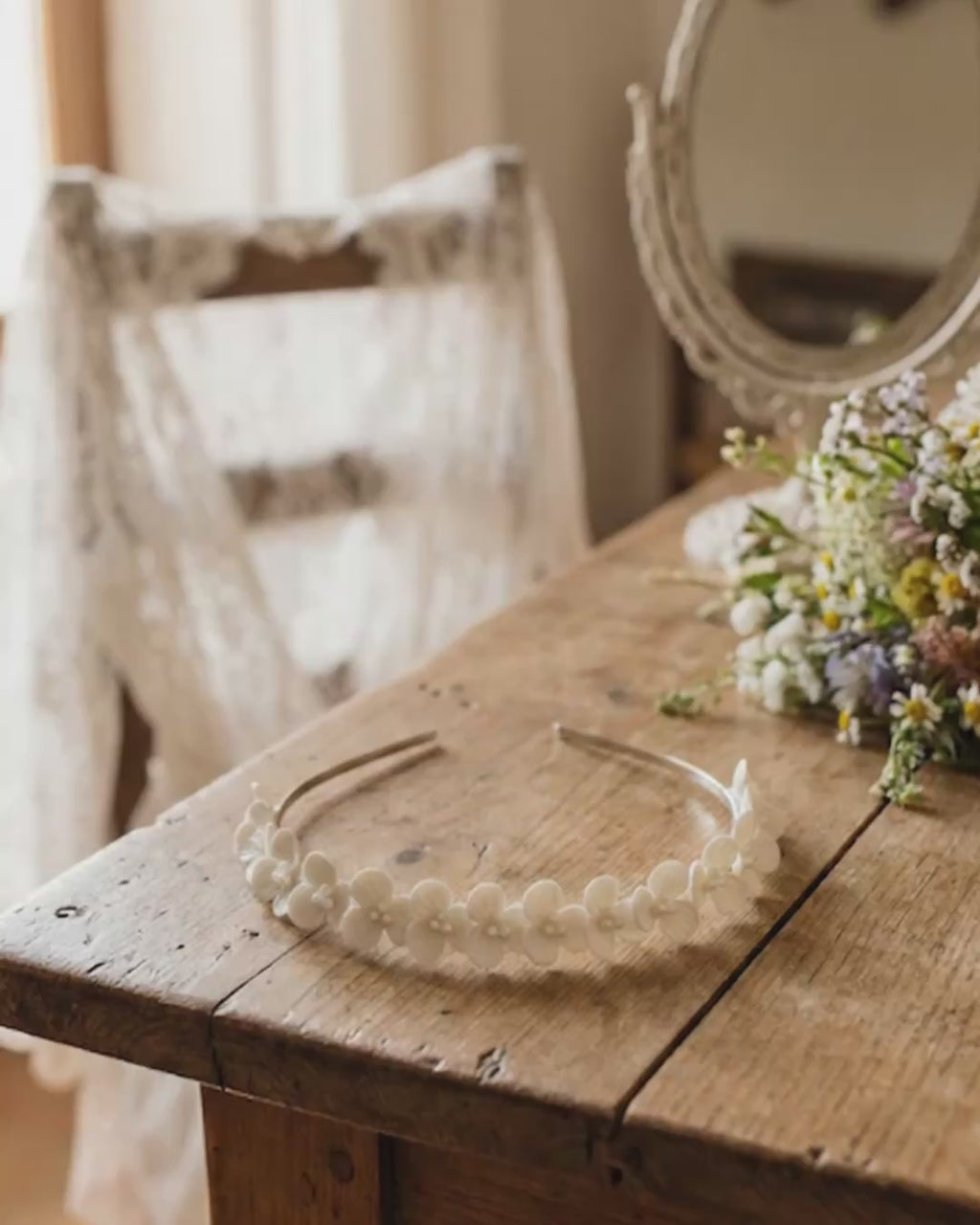 Video con zoom out que revela una diadema de flores de porcelana fría artesanal sobre una mesa de madera rústica, rodeada de elementos de boda vintage y flores naturales.